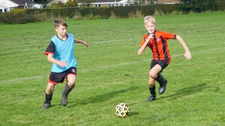 Children playing football in wellies