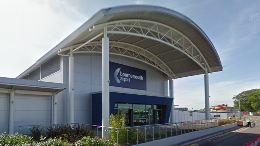 The entrance to the Bournemouth Airport terminal, a grey building with a curved roof.