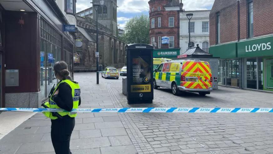 Police officer at a cordon with an ambulance on the high street