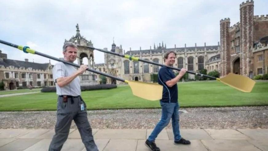 Men carrying oars spray-painted gold