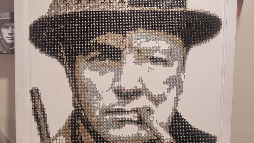 The artwork depicts half of Winston Churchill's face and half the face of an unknown soldier. It is black and white and made up entirely of screw heads, giving a dot matrix impression to the image. 