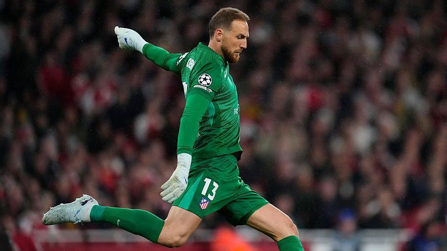 atletico madrid goalie Jan Oblak in a green kit kicking the ball