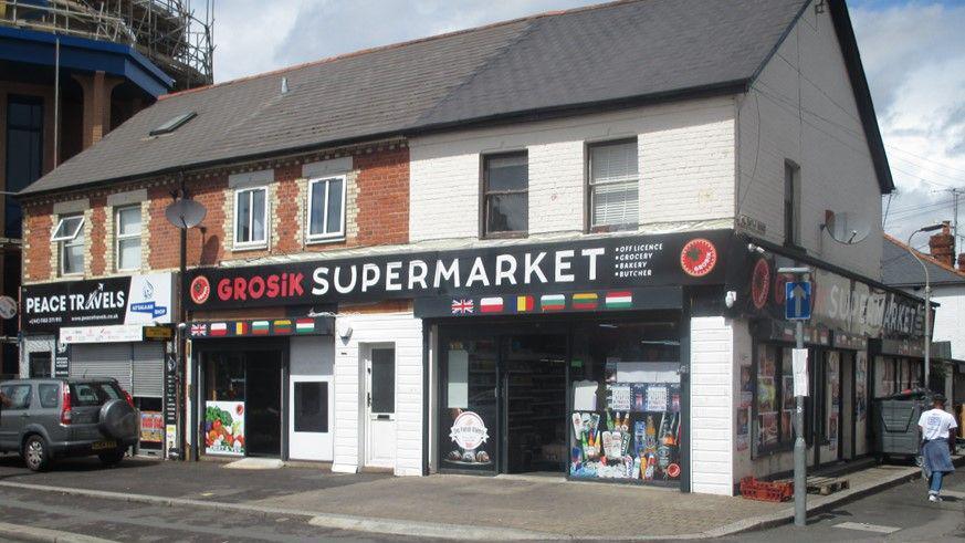 The front of Grosik Supermarket after the extension has bee removed. A person is seen walking down one of the side streets.