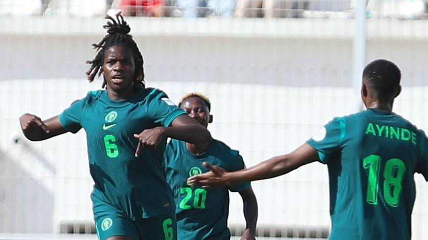Esther Okoronkwo in dark green Nigeria kit celebrates a goal against Zambia with two team-mates running towards her