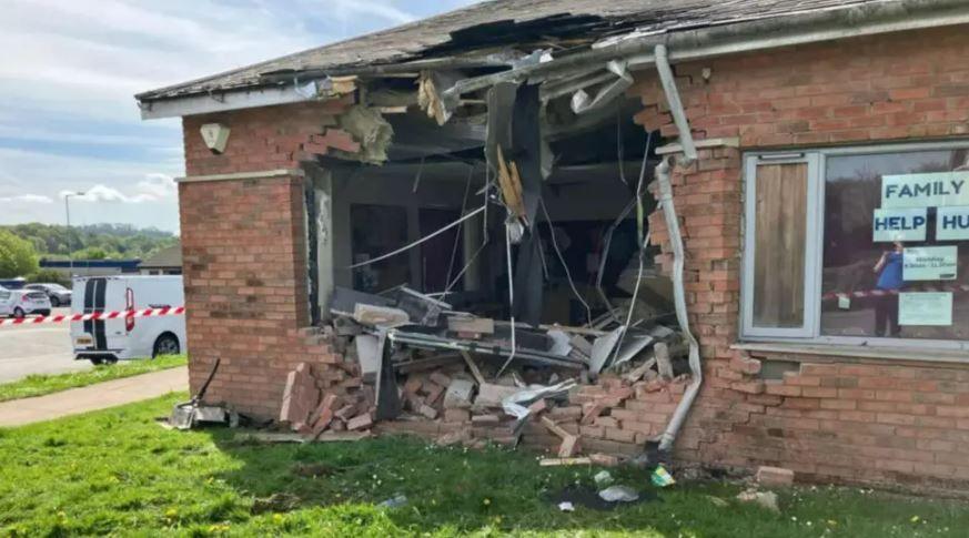 A one-storey brick building with a large hole knocked in one wall and red and white tape to the left