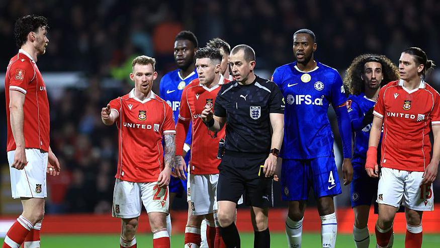 Lewis O'Brien of Wrexham speaks to Referee Peter Bankes as a VAR review takes place