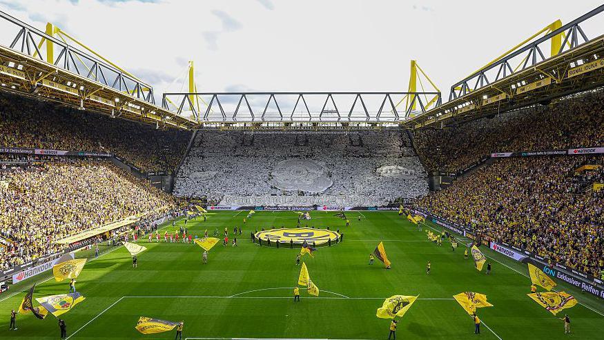 Borussia Dortmund's Signal Iduna Park stadium seen on August 31, 2025 with a fan choreography in one of the stands and yellow flags being waved on the pitch ahead of a match