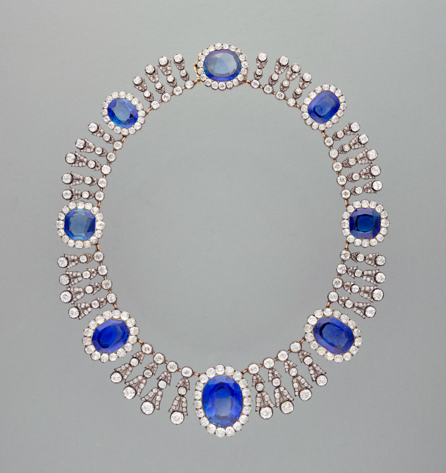 A silver necklace decorated with blue emeralds and diamons
