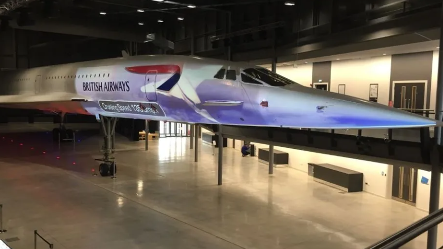 A Concorde model displayed in a museum, illuminated under bright lights