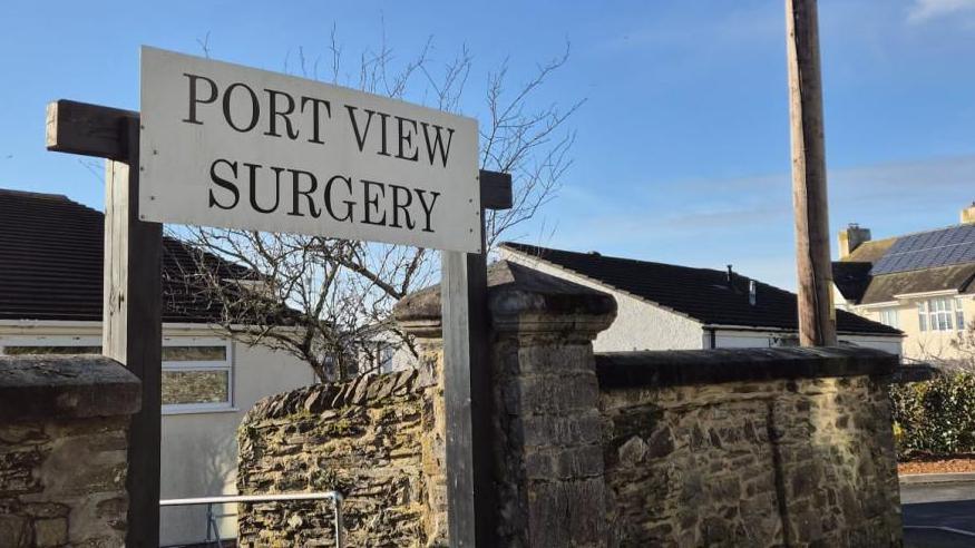 A sign for Port View Surgery over the entrance between a brown brick wall