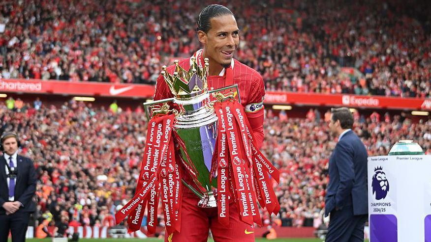 Virgil van Dijk of Liverpool carries the Premier League trophy to the winners stage