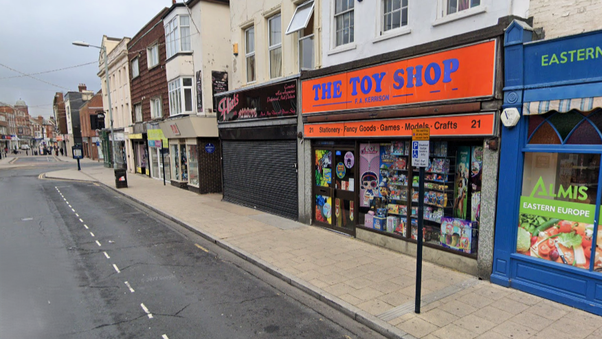 A street view image of Kerrison Toys on King Street in Great Yarmouth. The store has an orange facade and the words "The Toy Shop" are written in blue