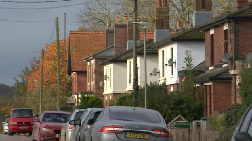 Red brick and white homes with cars parked outside. 