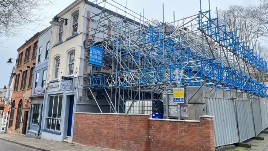 General view of the Brass Monkey bar. The right side of the building has blue and grey scaffolding along the wall.