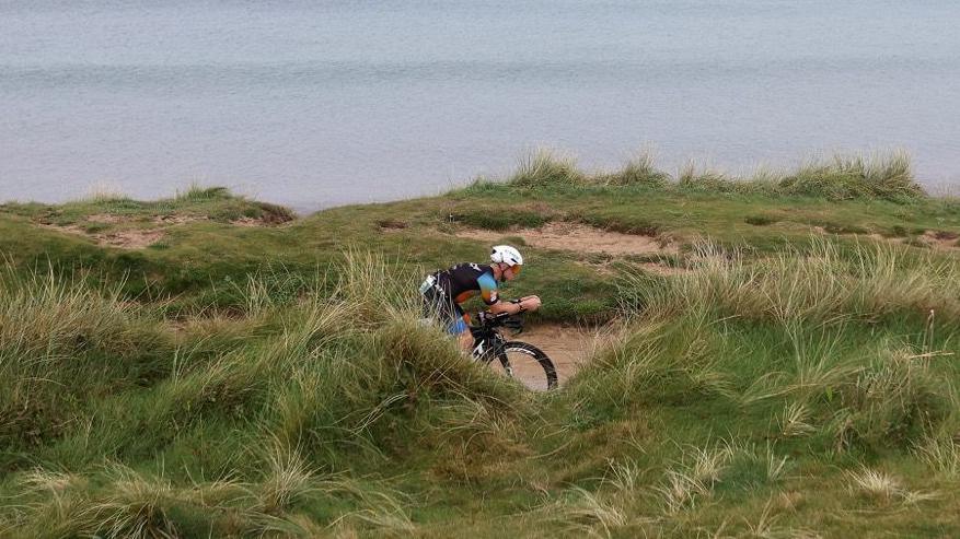 Cyclist riding bike over a clifftop by the sea