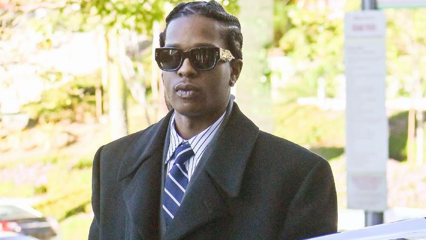 Rapper A$AP Rocky is photographed outside a courthouse in California wearing sunglasses and a suit. 