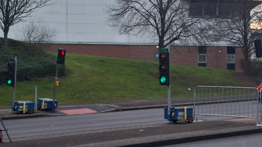 Two traffic lights are positioned either side of the main road enabling people to cross the main road