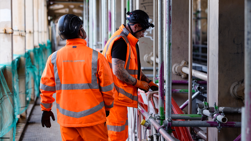 Two people in hi-vis clothing making repairs to the bridge