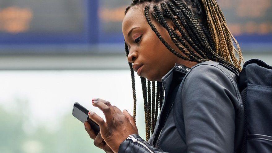 A woman walking through a train station while looking at her mobile phone