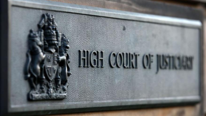Grey sign outside High Court in Edinburgh which reads High Court of Justiciary.