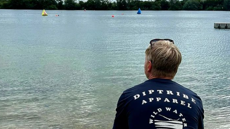 Paul Flynn looks out on Lake 32 with his back to the camera, wearing a jumper that reads 'Diptribe apparel' on the back