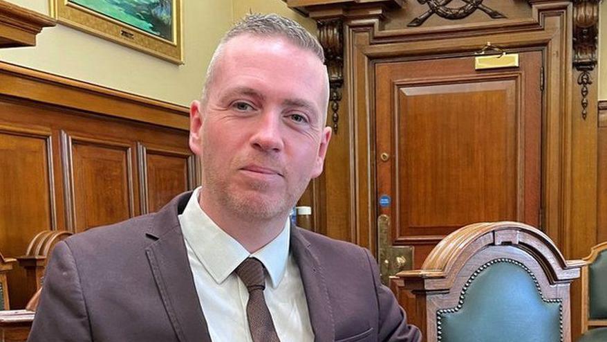 Mal O'Hara, leader of the NI green party, sitting in a council chamber