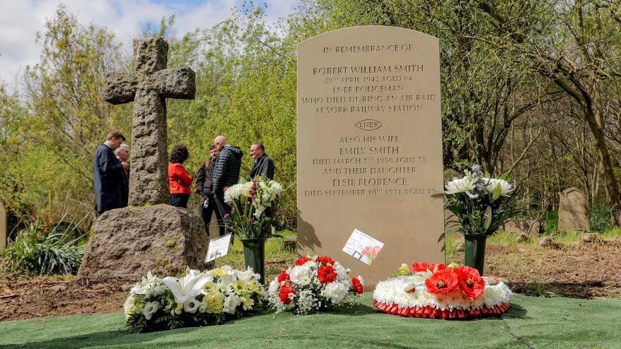 A close-up of Robert Smith's gravestone with wreaths laid in front