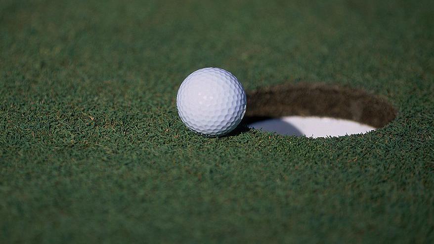 A general view of a golf ball sitting near a hole