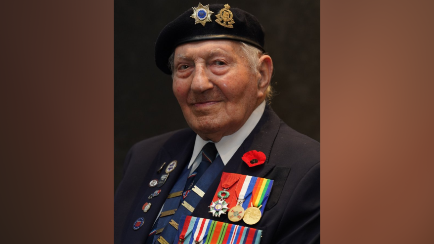 A headshot of Mr Kersh, who is wearing his unit beret and his medals and smiles at the camera