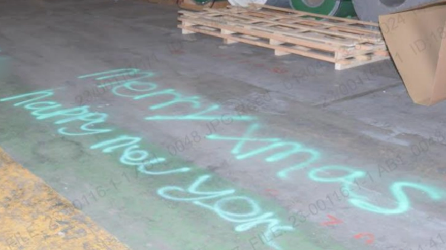 The words are written in green on the grey, concrete floor of a warehouse