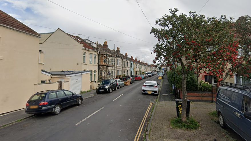 A Google street view of the entrance to Brittannia Street in Easton in Bristol. There are parked cars on each side of the street and the picture is taken on a bright, sunny day