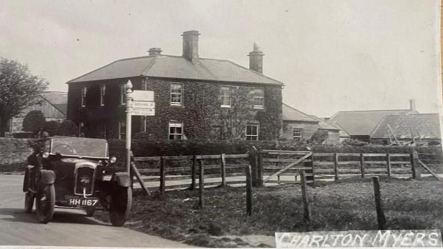 A black and white photograph dating from the 1920s shows a car of the era parked outside Charlton Mires, which is a square Georgian farmhouse. 