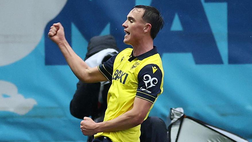 Luke Harris celebrating scoring for Oxford United by sliding on his knees.