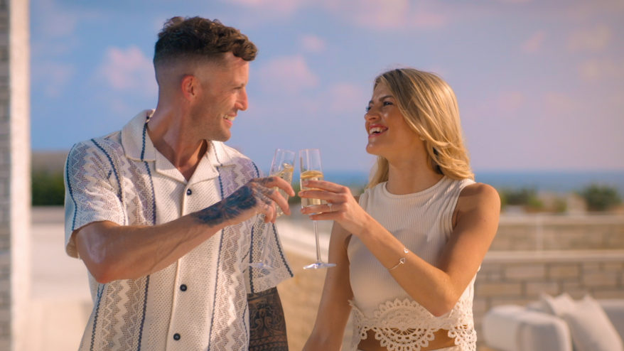 Billy and Ashleigh smiling at each other with a drink in hand