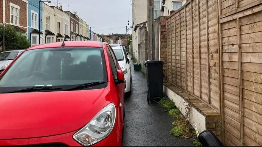 A photo of cars parked on the pavement, narrowing the street.