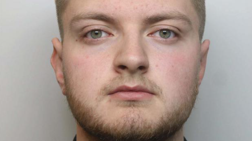 Bearded Mason Hodgson, wearing a black shirt, looks unsmiling and straight ahead in his police mugshot