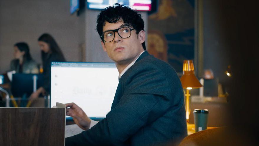 Clark Kent sits at a desk in the new Superman movie