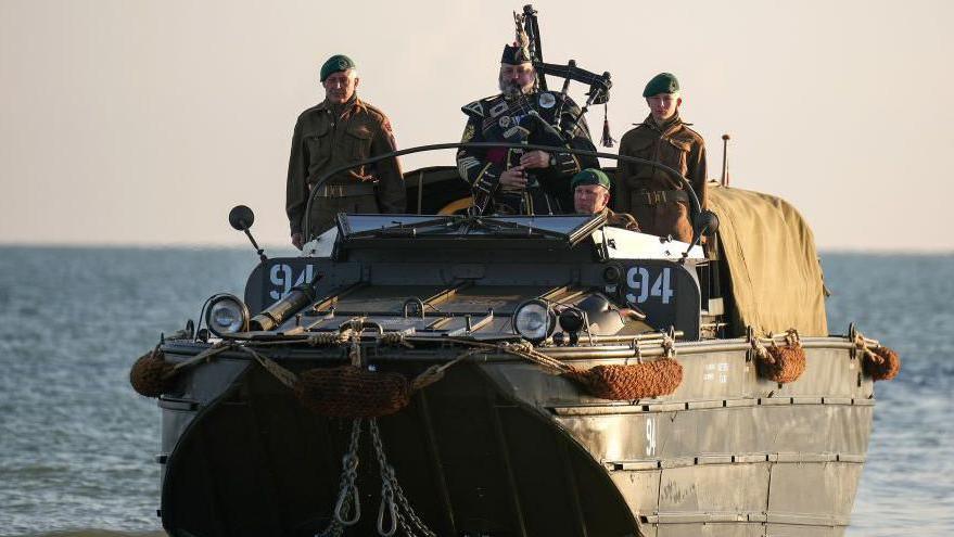 Pipe Major Trevor Macey-Lillie of the Scots Royal Artillery plays a lament as he arrives on Gold Beach in a WW2 landing craft at 07:26, the exact time 80 years ago that British troops stepped on to the beaches of Normandy