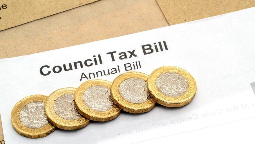 A stock image of the top of a generic council tax bill, with five £1 coins sitting on it.