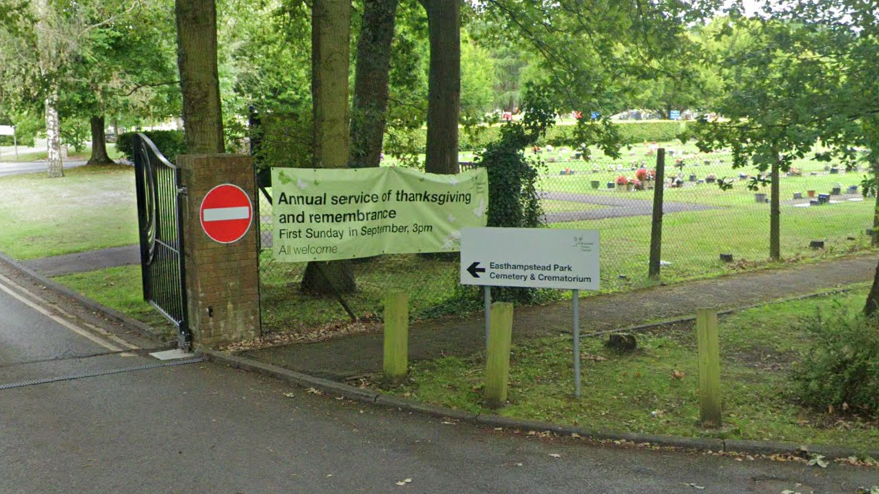 The gated entrance to Easthampstead Park Cemetery and Crematorium. A road runs through to the cemetery, and a field of gravestones can be seen in the background