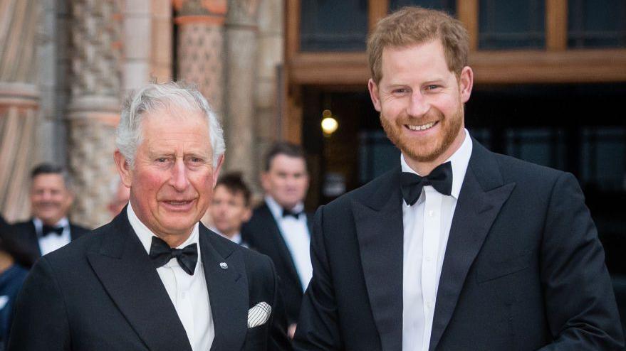 King Charles, then Prince of Wales, stands alongside Prince Harry, Duke of Sussex, at the "Our Planet" global premiere outside the Natural History Museum entrance. They are both dressed in black tie.  