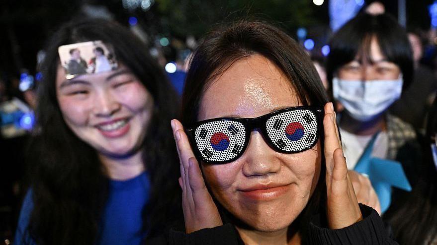 Supporters of Lee Jae-myung, the presidential candidate for South Korea's Democratic Party, shout slogans, with one wearing sunglasses adorned with the national flag.