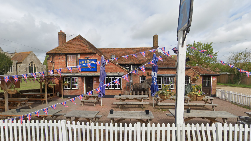 A red brick pub with benches and Union Flag bunting in the front garden.