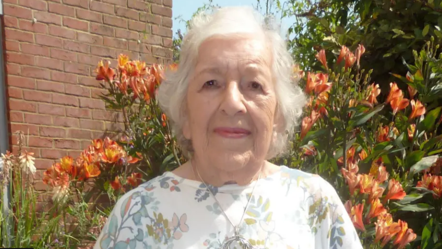 Phyll Babb standing in a garden with an abundance of orange flowers in the background