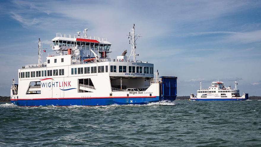 Two Wightlink ferries - Wight Sun and Wight Sky - passing in the Solent. They are roll-on, roll-off ferries, painted predominantly blue and white.