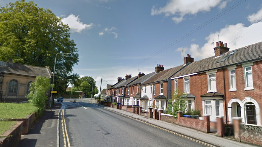 A Google maps screenshot of Devizes Road. IT is a straight residential street with terraced brick houses and an elevated grassy patch beside the pavement