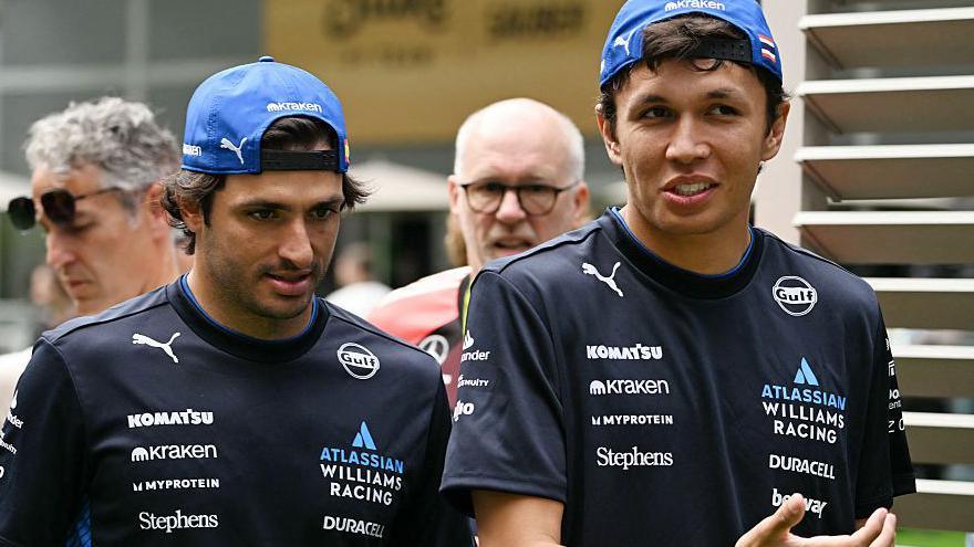 Carlos Sainz and Alex Albon in conversation at the Miami Grand Prix. Both men are wearing Williams t-shirts and caps back to front
