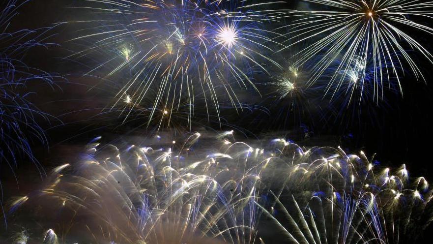 A number of fireworks which are blue, white and yellow can be seen against the backdrop of the night sky.