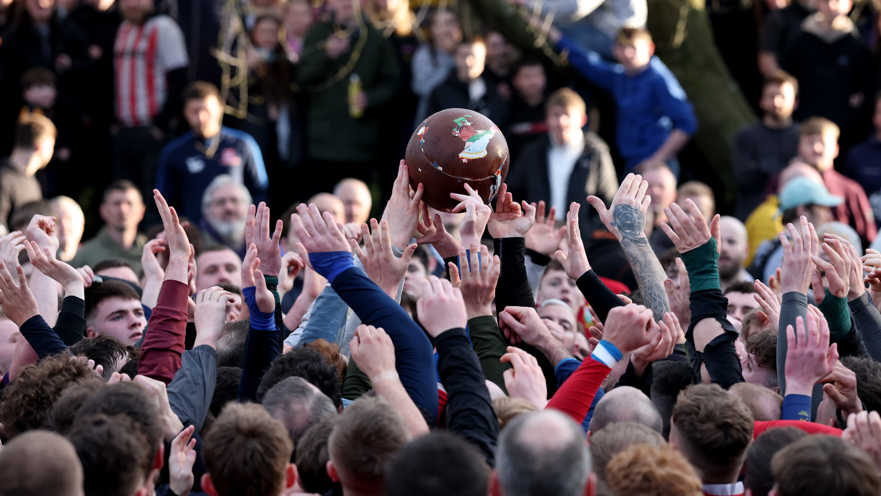 An image of dozens of people fighting for a football during Royal Shrovetide Football