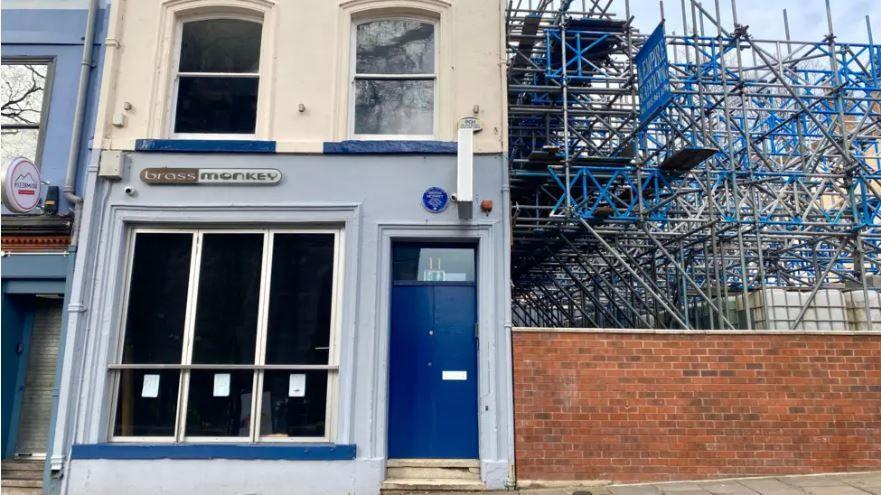 Closer view of the Brass Monkey bar. The right side of the building has blue and grey scaffolding along the wall.